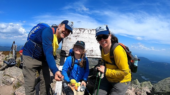 Two adults and a child on top of a mountain